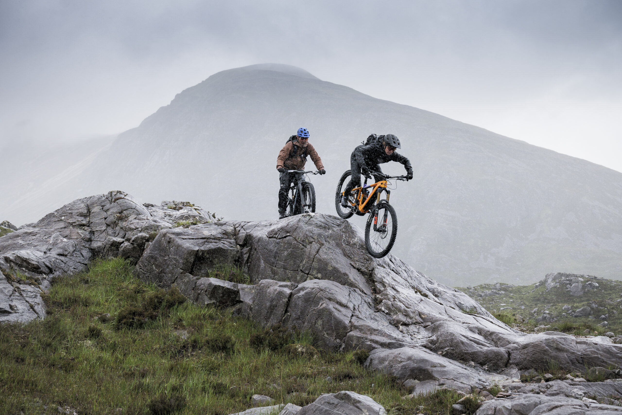 Two mountain bikers navigating rocky terrain in a dramatic landscape, showcasing adventure and skill by Ghost E-Riot Photo and Video Production. - Alexi Hall